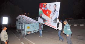 MC officials carry hoardings put up in Madhya Marg on Monday