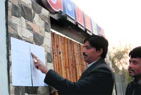 A HUDA official pastes a show-cause notice on the entrance of 'Five Degrees' restaurant of Sector 5 in Panchkula on Monday