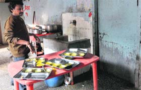 An employee of a private canteen cleans utensils outside the toilet near the Oral Health Department in Chandigarh on Monday
