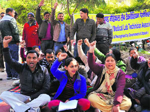 Laboratory technicians of government hospitals hold a demonstration at Doon Hospital in Dehradun on Monday. 