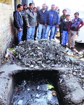 An uncovered manhole with garbage all around it near a gate of the General Bus Stand in Jammu