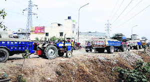 Sand-laden tractor-trailers parked on a road in Haibowal in Ludhiana on Wednesday.