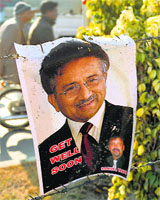A poster of Pervez Musharraf hangs on a barbed wire fence in front of the Armed Forces Institute of Cardiology in Rawalpindi on Thursday, where he is being treated.