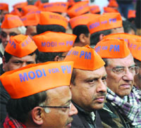 BJP leaders and workers sport saffron caps during the protest against the AAP government at Rajghat in New Delhi on Friday.