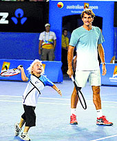 Roger Federer watches Cruz Hewitt, the son of Lleyton Hewitt, during the Kids Tennis Day before the Australian Open