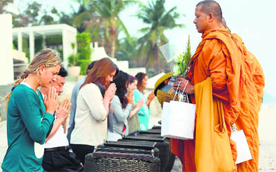 Tennis world number 2 Victoria Azarenka of Belarus (in blue sweater) gives food offering to Buddhist monks at Hua Hin beach, Prachuap Khiri Khan province, Thailand. Azarenka recently defeated Serena Williams in an exhibition match.
