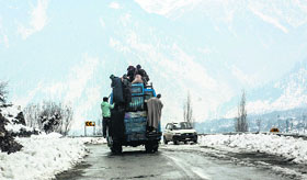  locals travel atop a bus amid snow-covered mountains and streets in Srinagar on Sunday.