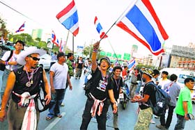 Anti-government protesters wave flags as their group arrives to block one of the city's key intersections as a part of their attempt to "shutdown" Bangkok on Sunday