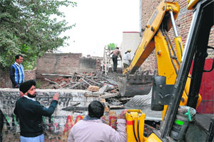 Encroachments being removed on the 100-feet road by the MCB team in Bathinda on Monday