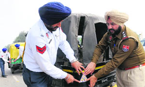 Officials paste a sticker bearing the police helpline number on an auto-rickshaw as part of Traffic Awareness Week at an intersection in Phase VII, Mohali, on Monday.