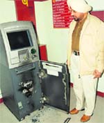 A policeman looks at the PNB ATM that was broken open with a gas-cutter in Jalandhar on Monday. A Tribune photograph 