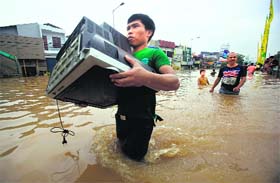 A man carries a television during a flood in Jakarta on Monday