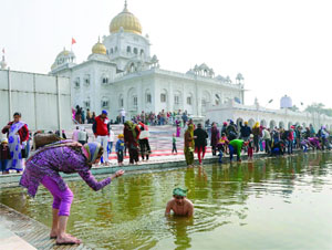 Devotees take a dip into the holy pond at Gurdwara Bangla Sahib on the occasion of Makar Sankranti in New Delhi on Tuesday