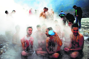 Devotees take a holy bath in a natural hot water spring near the bank of the Sutlej on the occasion of Makar Sankranti at Tattapani in Shimla on Tuesday