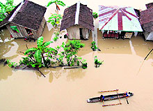 A boat passes by submerged houses due to flooding brought about by heavy rains on the outskirts of Butuan City in Philippines on Tuesday. Twenty-two people have been killed in the southern Philippines region