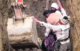 Workers try to rescue the labourers buried under a mound of earth in Amritsar on Thursday