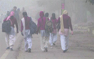 Amidst dense fog, girls on their way to school in Amritsar on Friday. 