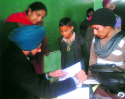Chairman of the Zila Parishad Gurpreet Singh Maluka examines the official records at a government school in Bathinda on Friday.