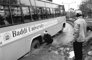 A worker clears mud around the rear tyres of a Baddi University bus that got stuck in a pit at the MDC in Sector 5, Panchkula, on Saturday. 