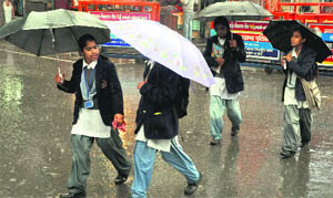 Girls on their way to school during a rainy morning in Dehradun on Saturday. 