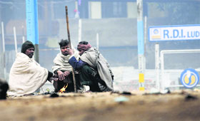 Workers sit around a bonfire on a chilly Saturday afternoon in Ludhiana.