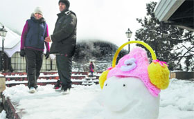 A tourist couple stand near a snowman in Shimla on Sunday.