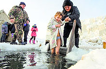 A girl smiles as she is helped to get into the ice-cold water of the Ob River after it was blessed by an Orthodox priest on Epiphany in Moscow on Sunday