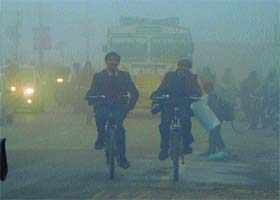 Foggy view: Schoolchildren bicycle through thick morning in Amritsar on Monday