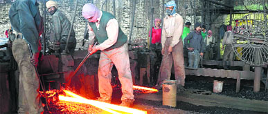 Workers busy operating machines at one of the re-rolling mills in Mandi Gobindgarh.