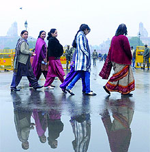 Women cross Rajpath during the rain in New Delhi on Tuesday