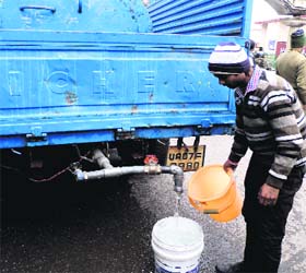 A man fills a bucket with water from a tanker sent by the Jal Sansthan authorities