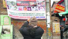 A tourist takes a picture of a banner at Gaw Kadal on the 24th anniversary of the massacre in Srinagar on Tuesday.