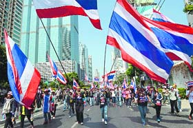 Protesters wave national flags as they march during their ongoing rallies in Bangkok on Tuesday