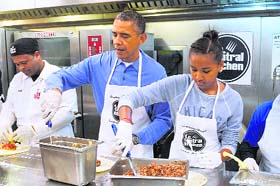 President Barack Obama and his daughter Sasha take part in a community service project, making burritos at DC Central Kitchen, in celebration of the Martin Luther King Jr. Day on Monday in Washington, DC