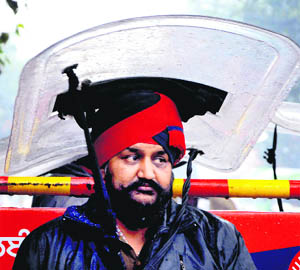 A policeman deputed outside the municipal corporation office in view of the protest by a Congress councillor tries to shelter himself from the rain that lashed the city since Wednesday morning.