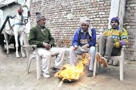 BEATING THE CHILL: People sit around a bonfire to drive away the cold on Amrik Singh Road in Bathinda