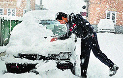 A youth clears snow from his vehicle in Srinagar on Wednesday