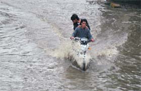 Two youths riding a motorcycle wade through a waterlogged stretch on Damoria Bridge in Ludhiana on Wednesday
