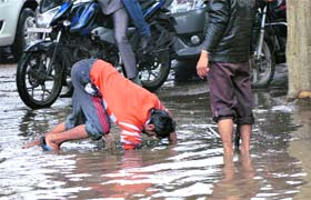 A man tries to open a choked drain near Bhai Bala Chowk