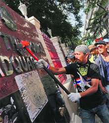 A protester destroys the sign of the Royal Thai Police at its headquarters in Bangkok on Wednesday.
