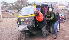 An auto stuck in slush and residents forced to take a broken road at Jagatpura village