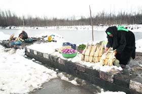 A woman sells vegetables on the banks of the Dal Lake in snow-bound Srinagar on Thursday