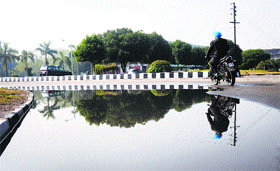 A motorcyclist avoids a pool of water on the road as he rides past a roundabout on the PAU campus.