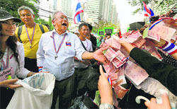 Supporters hand over money to Thai anti-government protest leader Suthep Thaugsuban during a march in Bangkok on Thursday. AP/PTI