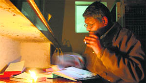 A doctor forced to work in candlelight owing to a power cut at the General Hospital, Rohtak, on Friday.