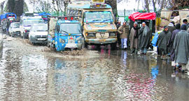 Vehicles pass through a waterlogged road at Hazratbal in Srinagar on Friday.