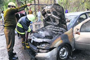 A fire-fighter douses the flames that engulfed a car on the Kaimbwala road on Monday. 