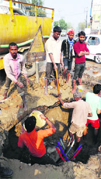 Workers of a cable network company try to repair the water and sewer pipes on Bhagu Road in Bathinda. 