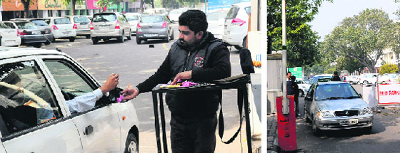 A worker gives a parking slip to a visitor at a parking lot in Sector 17 on Wednesday; and (right) the automated system not being used at the parking lot. Tribune photos