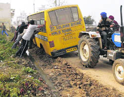 Farmers pull out a trapped school bus with the help of a tractor near Phagwara on Wednesday.